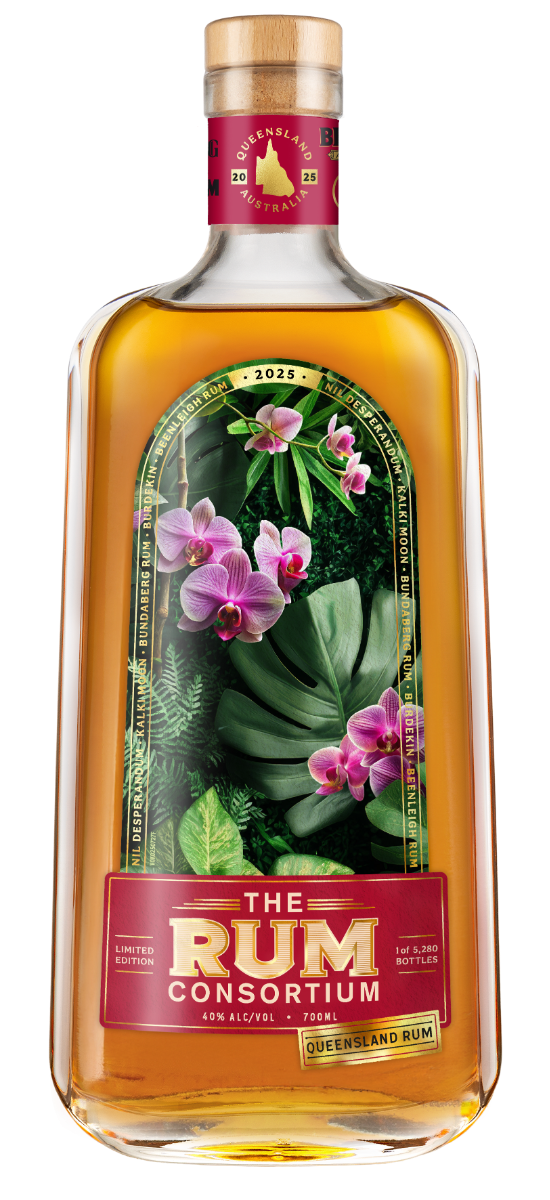 A clear glass rum bottle displays a botanical label with pink orchids and green leaves; amber liquid fills the bottle against a white background.