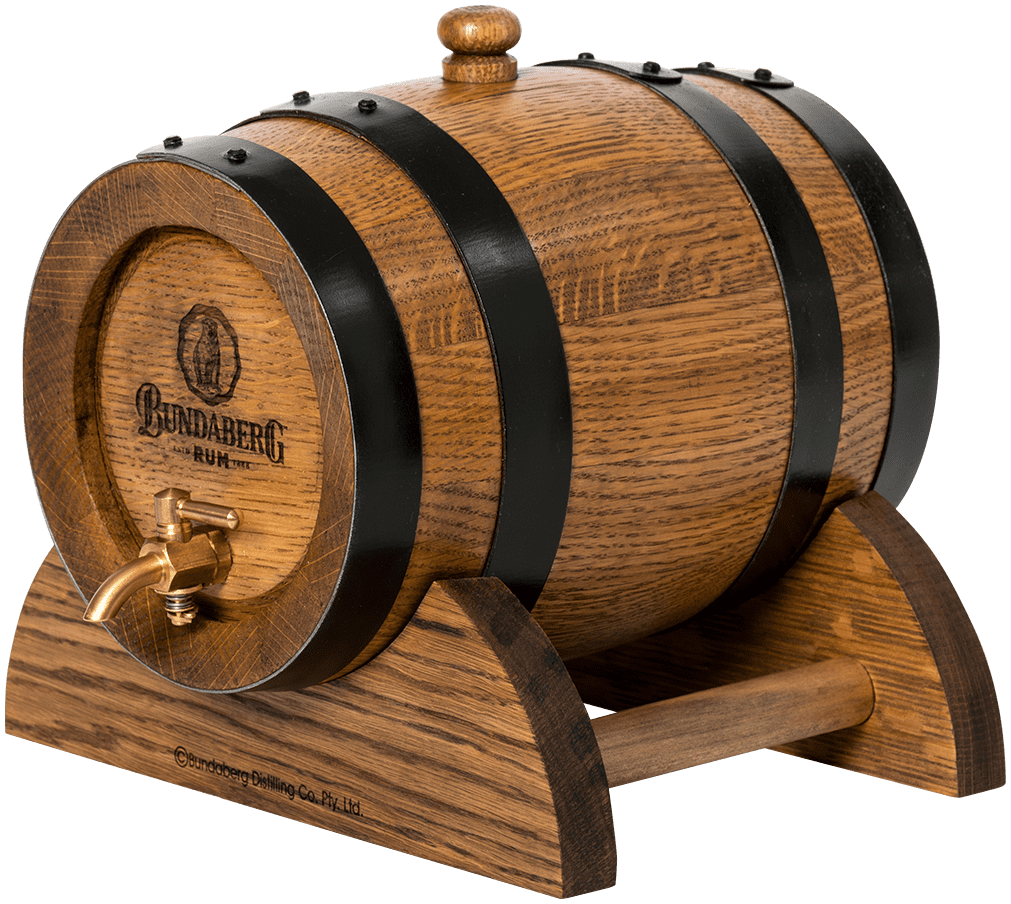 Oak rum barrel sits on a curved wooden stand, fitted with a brass tap and black metal hoops, photographed against a plain white background.