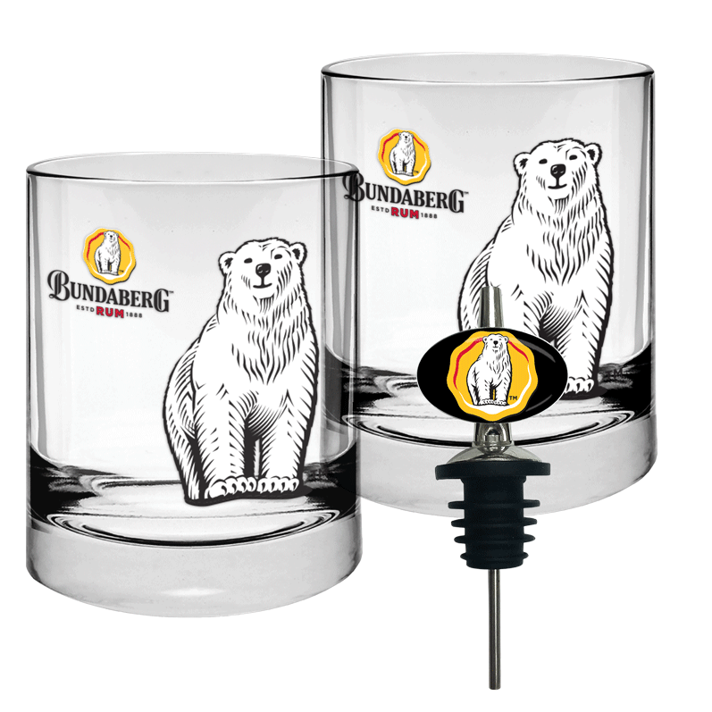 Two short clear glass tumblers printed with standing polar bear illustrations and a Bundaberg logo, accompanied by a black bottle pourer with stopper, arranged on a white background.
