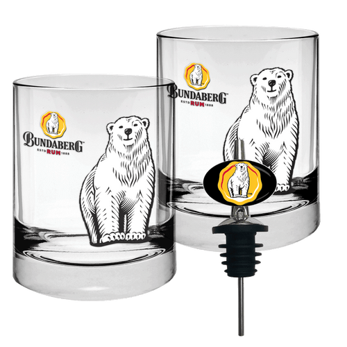 Two short clear glass tumblers printed with a standing polar bear; one fitted with a black bottle pourer, arranged on a white background as a product shot. Text: small, illegible characters beside circular logo.