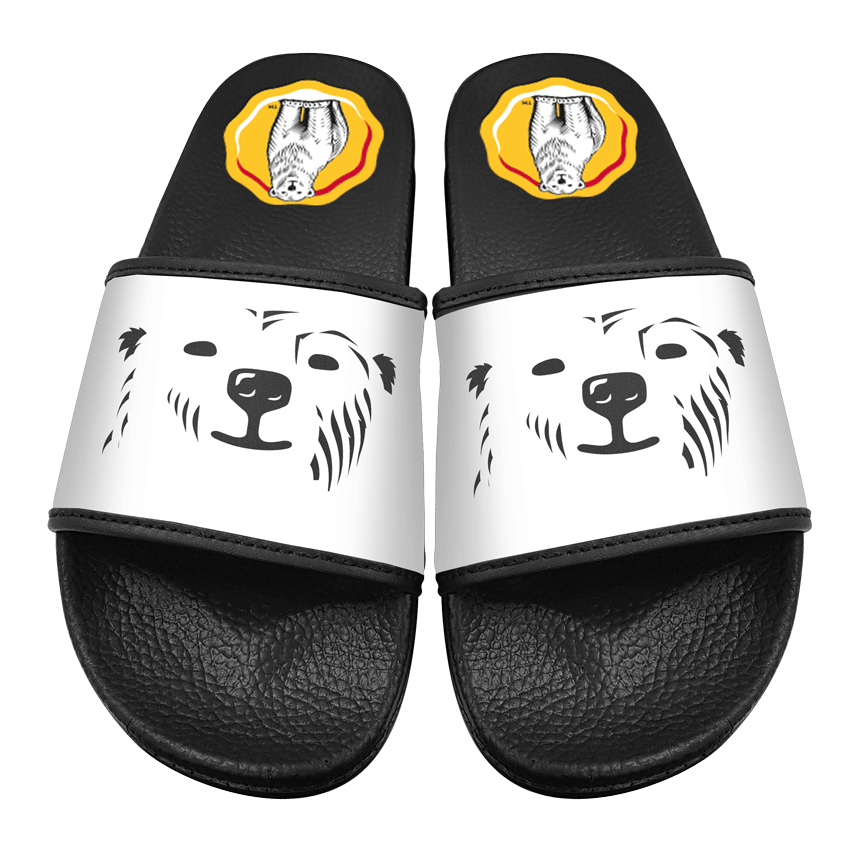 Pair of black-and-white slide sandals display cartoon polar bear faces across the white straps, with yellow circular logos in the footbeds, positioned side-by-side on a plain white background.