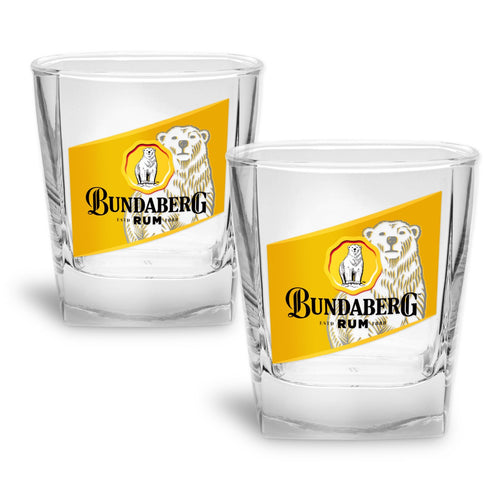 Two clear short glass tumblers displaying a yellow diagonal label with a polar bear logo; glasses sit side-by-side on a white background.