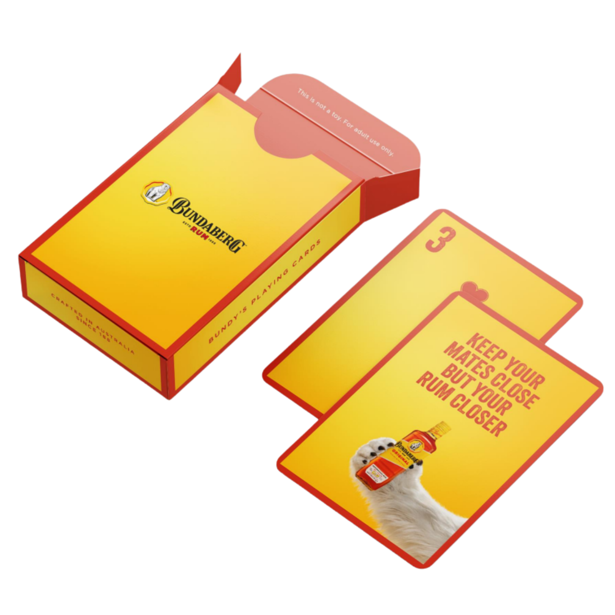 Yellow-and-red game deck box sits open; a matching card (number 3) lies beside, showing a hand holding a small bottle — isolated on a white background. Text on card is too small/blurred to transcribe accurately; please provide a clearer crop for full transcription.