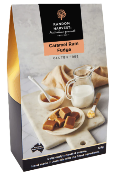 A rectangular box of confectionery sits angled on a marble surface; packaging photo shows caramel fudge squares on a plate with a small jug of milk and a spoon.