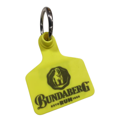 Yellow plastic key tag attached to a metal split ring, printed with a bear-in-crest Bundaberg logo; text reads: "BUNDABERG" and "ESTD RUM 1888".
