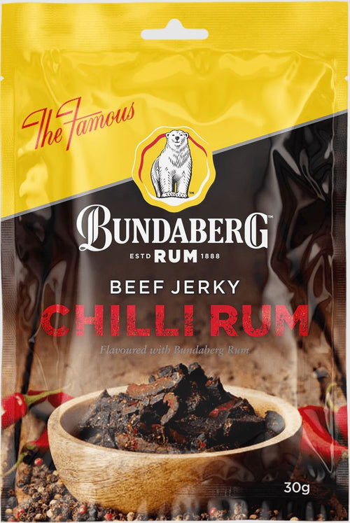 Bundaberg Rum–branded packet of chilli rum beef jerky standing upright, showing a wooden bowl of dark jerky and red chilies on a rustic surface.