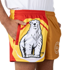 Shorts featuring a large illustrated polar bear on the front; person stands cropped at the hips with one hand in a pocket, wearing a white shirt and red-yellow-orange sport shorts on a white background.