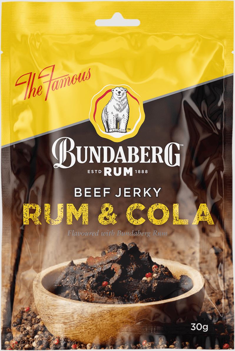 A standing packet of Bundaberg Rum Beef Jerky (Rum & Cola) in yellow and brown packaging, positioned behind a wooden bowl of dark jerky on coarse spices.
