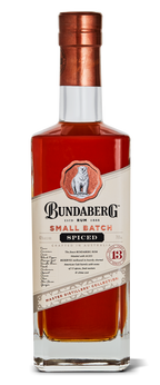 A tall rectangular glass bottle of Bundaberg Small Batch Spiced rum stands upright, amber liquid visible; cream-and-red label with crest and copper-colored cap, isolated on a white background.