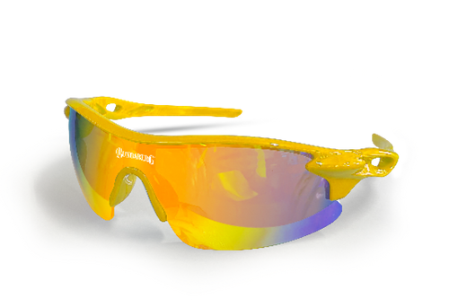 Yellow wraparound sports sunglasses sit on a flat surface, their mirrored orange-to-purple lens reflecting light; small white logo printed on the left lens (text illegible).